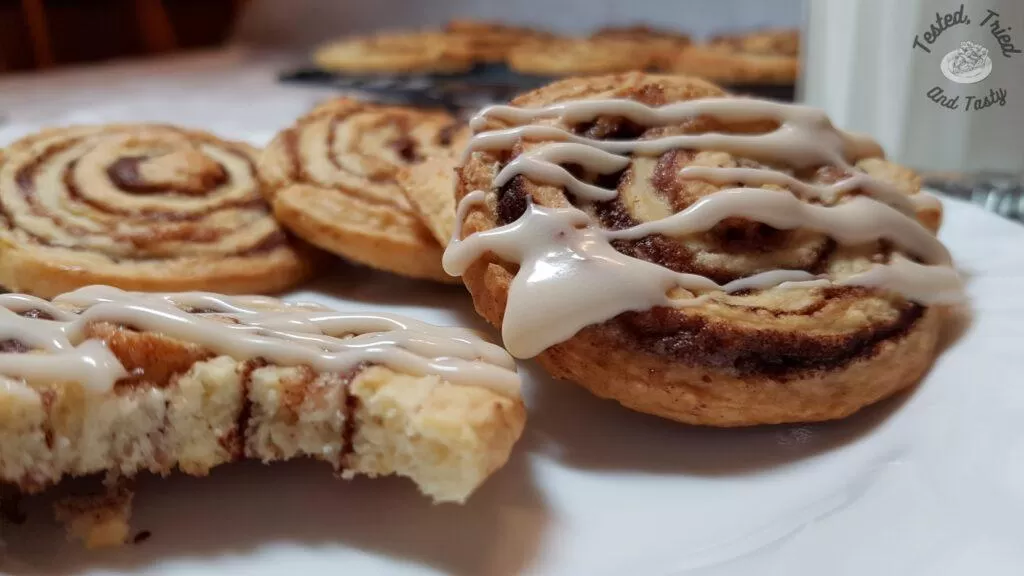 Cinnamon roll cookies on a plate with a glass of milk.