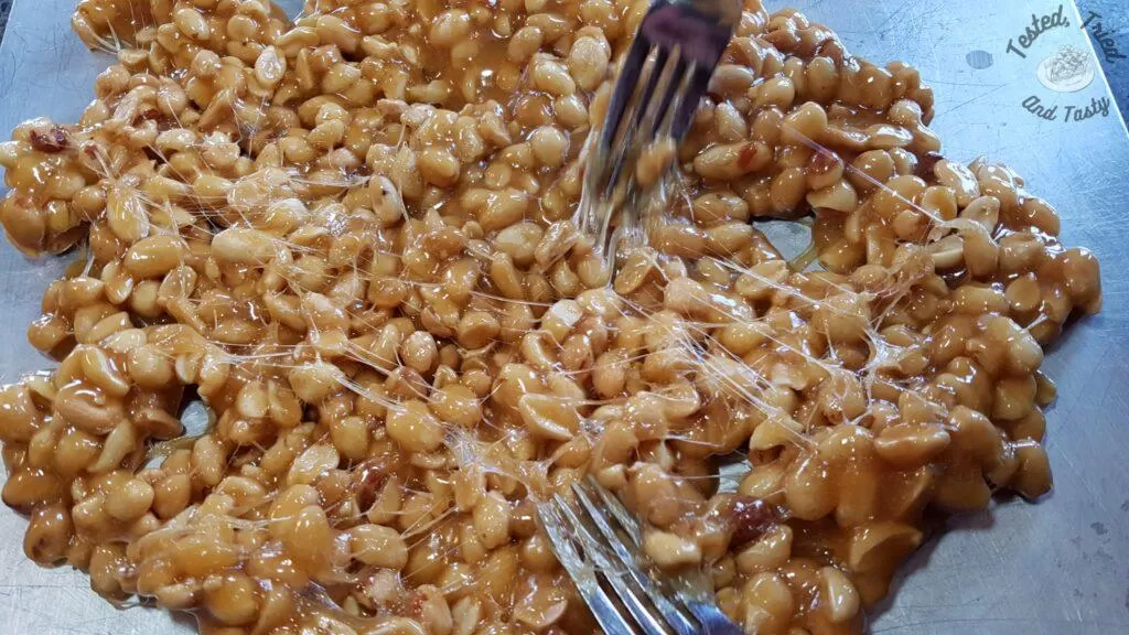 Pulling apart the peanut brittle candy with 2 forks.