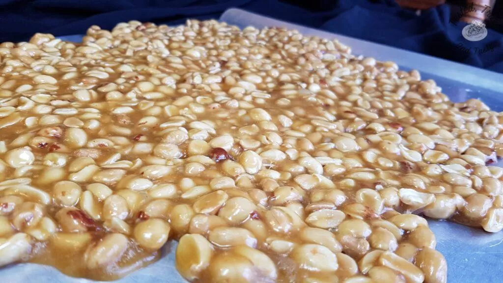 Candy peanut brittle cooling on a baking sheet.