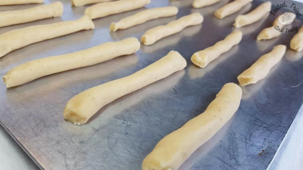 Egg nog cookies shaped into small logs on a baking sheet.