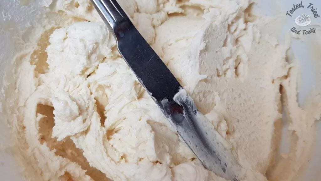 Vanilla icing in a white bowl.
