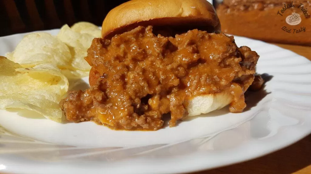 Sloppy Joes recipe on a bun with chips on the side.