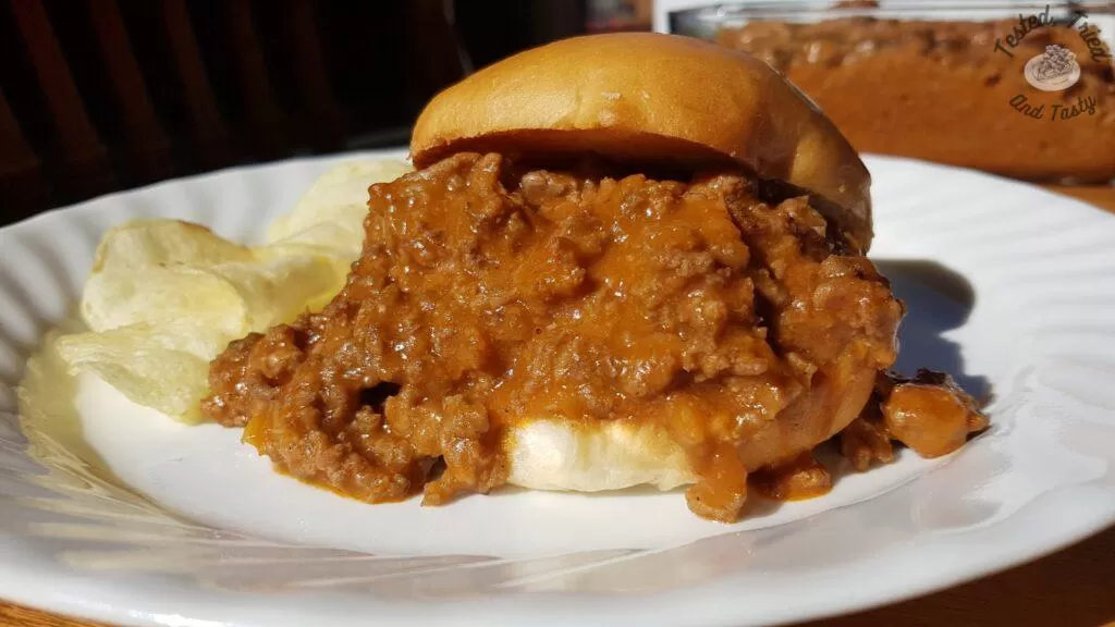 Sloppy Joes recipe on a bun with chips on the side.
