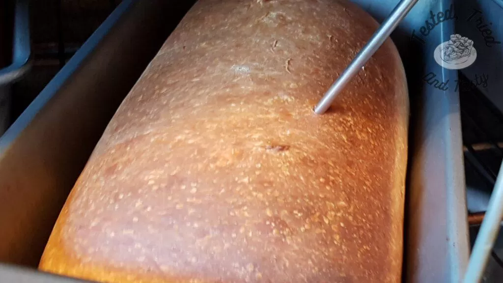 Checking the temperature of a finished sourdough bread loaf.