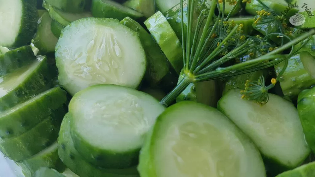 Dill, garlic and sliced cucumbers in a plastic buckent.