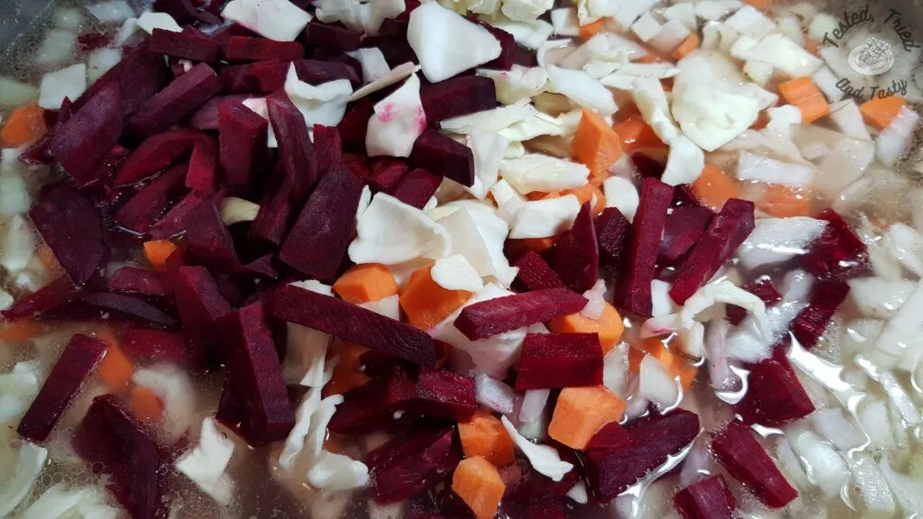 Beets onions, carrots and cabbage added to broth in a large saucepan.