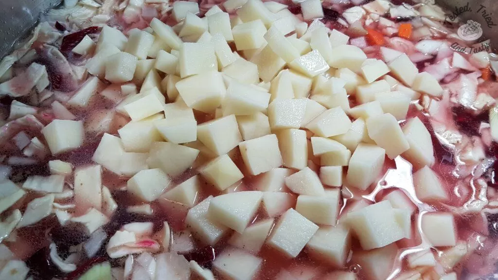Potatoes added to the vegetables in a large saucepan.