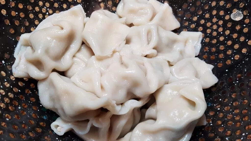 Cooked wontons in a strainer.