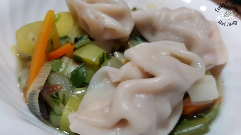 Wor wonton soup in a white soup bowl.