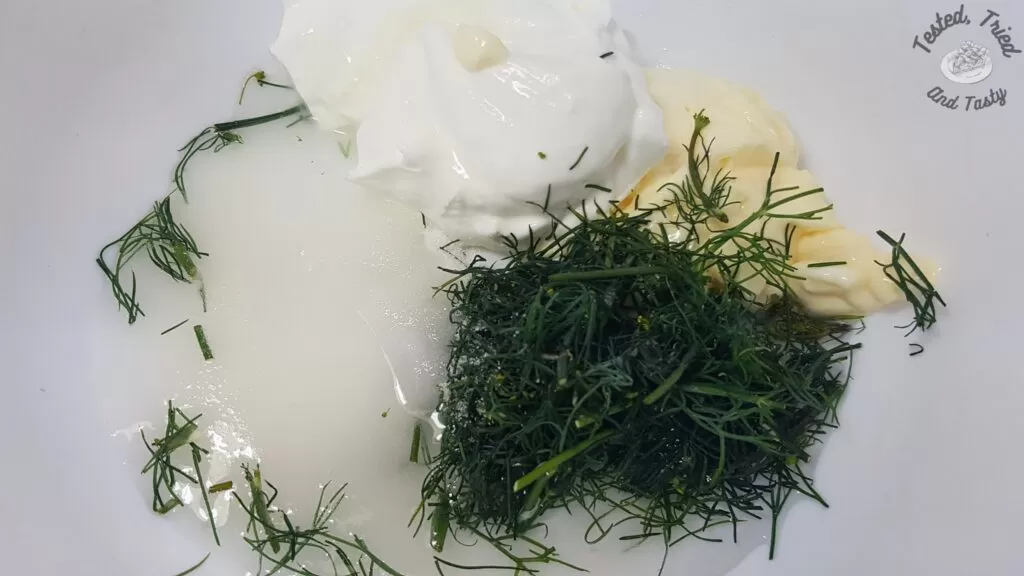 Ingredients for creamy dill dressing in a white bowl.