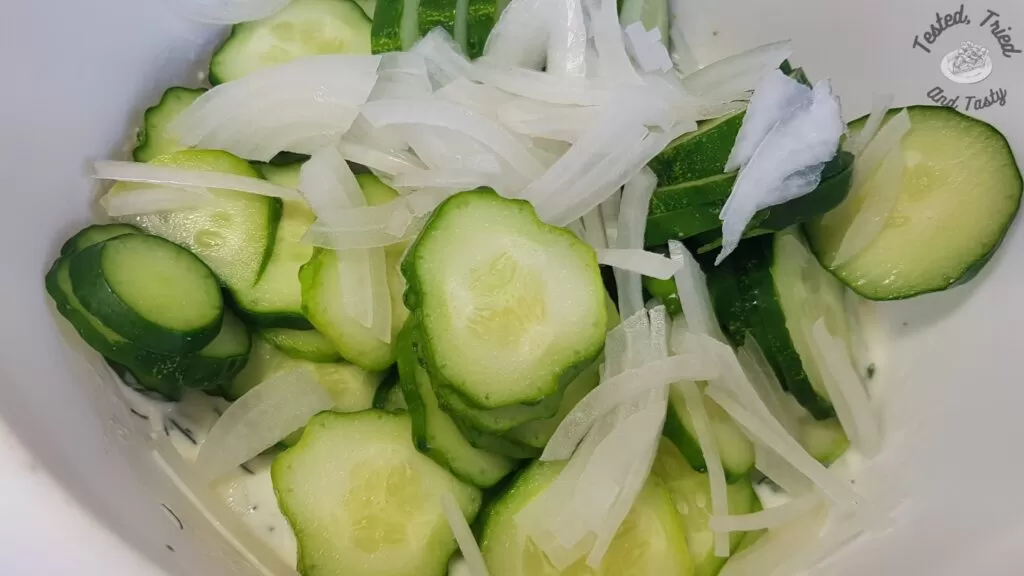 Sliced cucumbers and onions ready to mix with dressing for creamy cucumber salad.