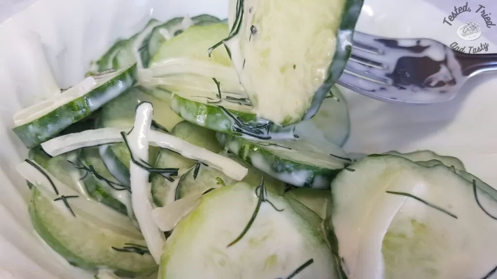 Creamy cucumber salad in a white bowl.