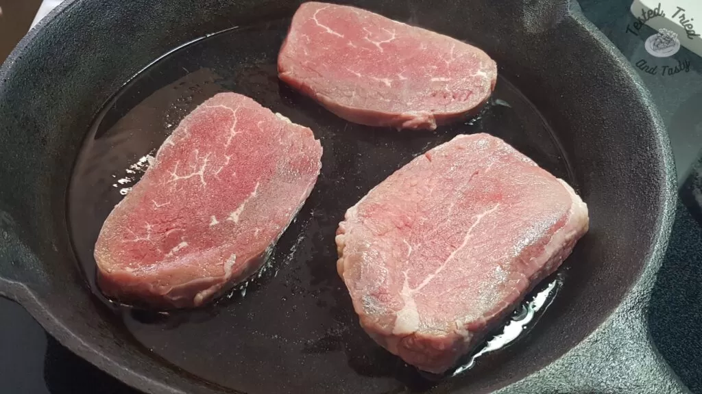 Beef browning in a cast iron pan.