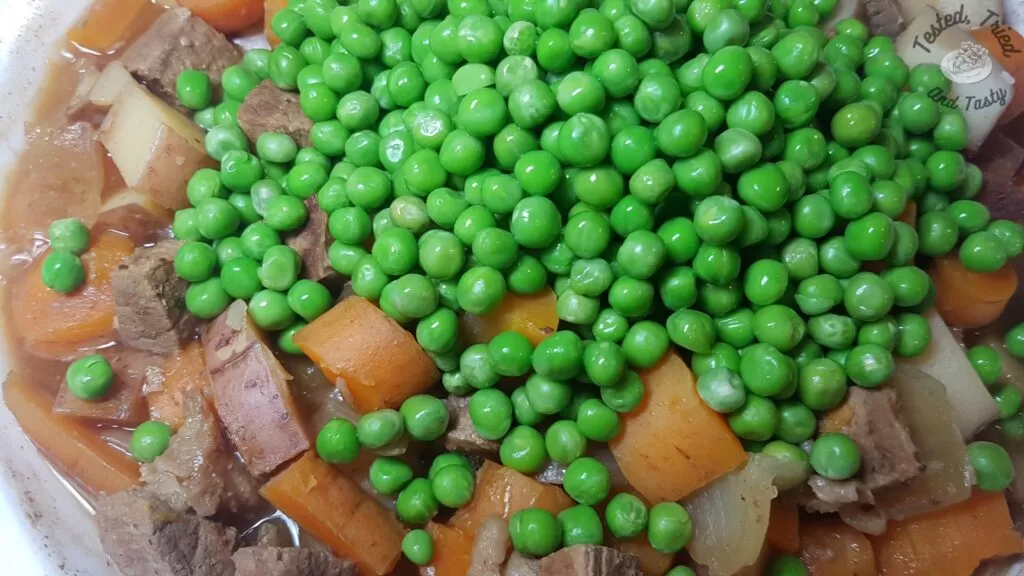 Adding the peas at the very end of cooking the beef stew in the crock pot.