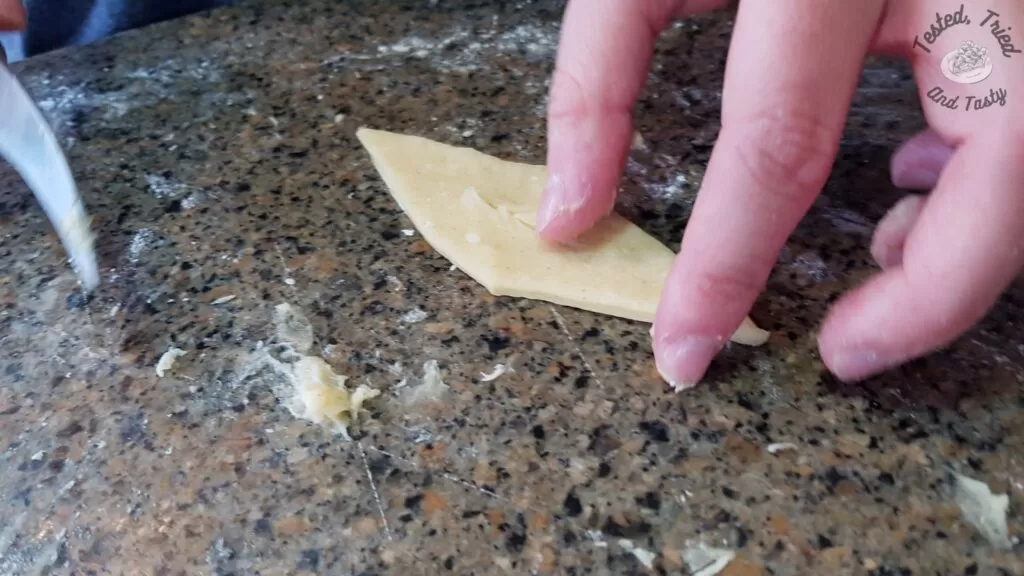 Cutting a slit in the center of the diamond shaped dough for Fattigman.