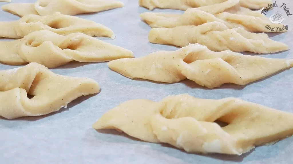 Fattigman on a parchment lined baking sheet waiting to deep fry.
