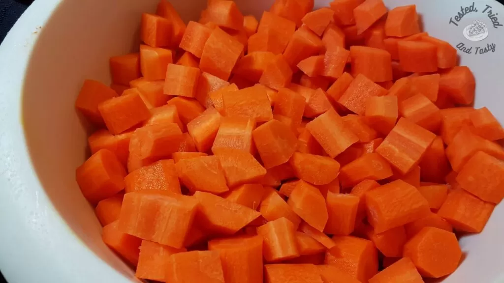 Bite size pieces of carrots in a white plastic bowl.