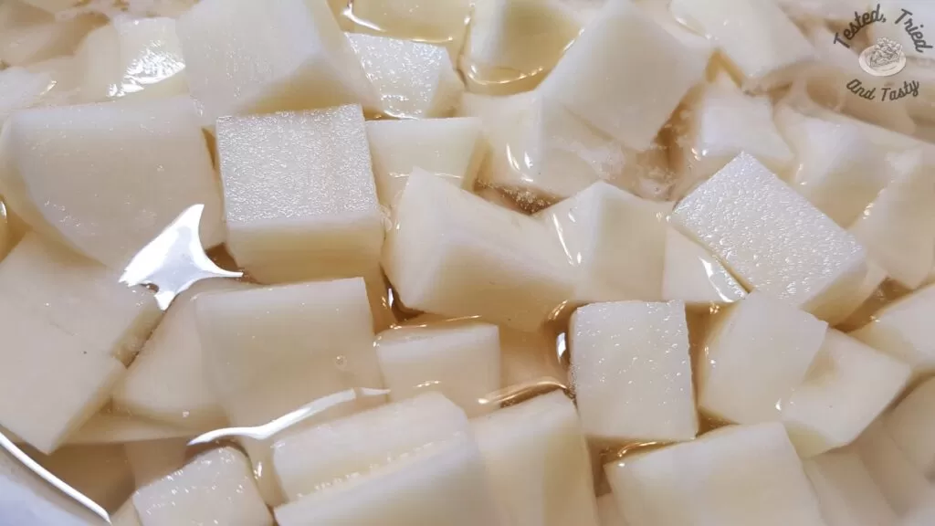 Bite size pieces of russet potatoes in water.