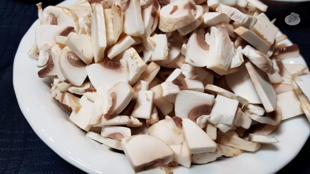 Sliced mushrooms in a white bowl,